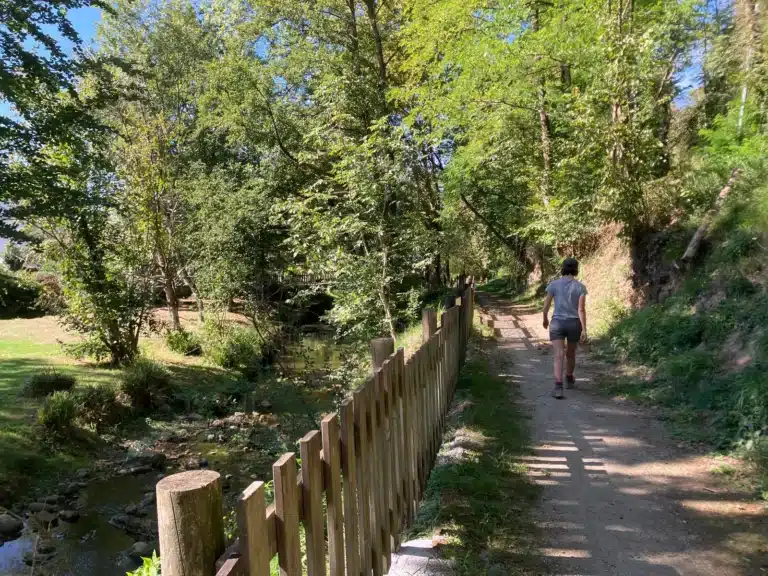 Chemin longeant le ruisseau, bordé d'une barrière en bois